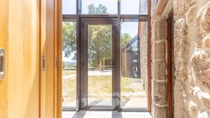 Ein modernes Interieur mit Glastür zu einem Außenbereich, Steinwänden und Fliesenboden.