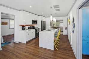 A modern kitchen with white cabinetry, stainless steel appliances, and a marble island with bar seating. - Nokomis Sunset Retreat  w/Pool - 8 mins to Beach (Nokomis)
