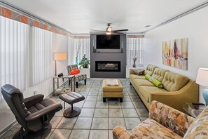 A living room with a fireplace, a sofa, a chair, and a television. - Nokomis Sunset Retreat  w/Pool - 8 mins to Beach (Nokomis)