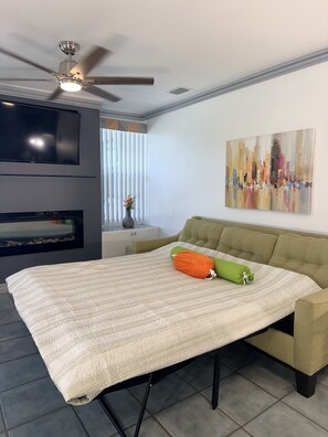 Un salon moderne avec un téléviseur à écran plat, un ventilateur de plafond, un canapé et un tableau accroché au mur.