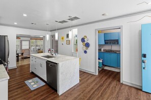A modern kitchen with a marble countertop, a dishwasher, and a blue cabinet. - Nokomis Sunset Retreat  w/Pool - 8 mins to Beach (Nokomis)