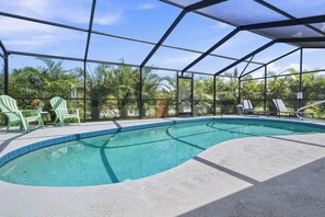 Une piscine intérieure offrant une vue dégagée sur la végétation environnante, un espace salon couvert et une table située au bord de la piscine.