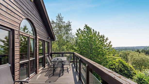 Een houten terras met tafel en stoelen, met uitzicht op een weelderig landschap.