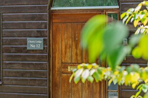 Una puerta de madera con picaporte de latón y un cartel que indica 'Cherry Lodge No 12'.