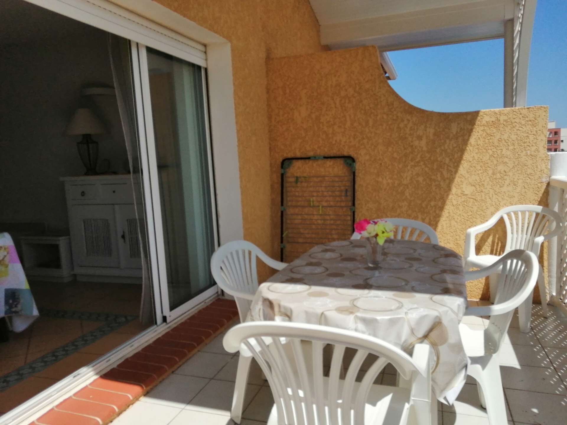 Ein Balkon mit Tisch und Stühlen, eine Schiebetür und ein kleines Schranksystem.