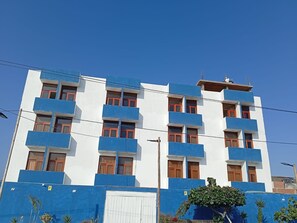 A multi-story building with balconies and a white and blue facade. - Hostal Lobitos (Cerro Azul)