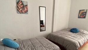 Una habitación con dos camas, un espejo y obras de arte en las paredes.