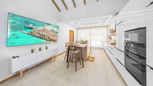 A modern kitchen with a large TV, a dining area, and a kitchen island. - Hideaway Aruba: Private Villa with Jacuzzi (Savaneta)