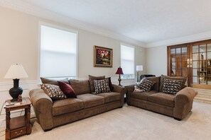 Ein Wohnzimmer mit zwei braunen Sofas, einem kleinen Holztisch, einer Lampe und einem Gemälde an der Wand.