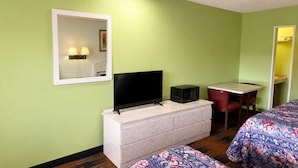 Quarto de hotel com televisão, micro-ondas, escrivaninha e duas camas.