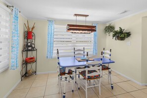 A dining area with a blue table and white chairs, a fan, and a plant on the wall. - Nokomis Sunset Retreat w/Patio 8 mins to  Beach (Nokomis)