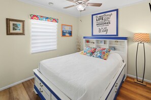 A bedroom with a bed, a ceiling fan, a window with blinds, a wall with framed pictures, and a floor lamp. - Nokomis Sunset Retreat w/Patio 8 mins to  Beach (Nokomis)