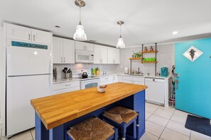 Eine moderne Küche mit weißen Schränken, einer Holztischinsel und einer blauen Akzentwand.