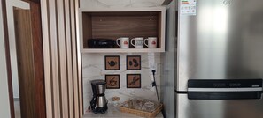 A kitchen with a coffee maker, mugs, and a refrigerator. - BREEZE HOUSE - VILA DO PERÓ - CABO FRIO, RJ, BRAZIL (Cabo Frio)