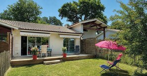 Ein Haus mit Terrasse, überdachtem Bereich und einem umzäunten Garten.