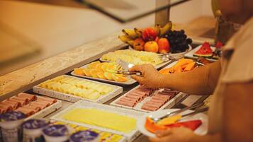 A buffet with various food items including fruits, pastries, and meats.