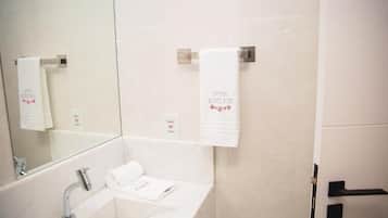 A bathroom with a sink, mirror, and two towels hanging on towel racks.