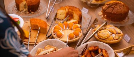 A buffet with various food items including cakes, pastries, and bread.