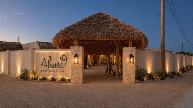 A boutique hotel entrance with a thatched roof, stone pillars, and a sign. - Boutique Studio | King Bed & Pool | Unit 1 | Aluna (Savaneta)