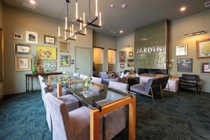 Eine moderne Hotellobby mit einem Esstisch mit Glasplatte, bequemen Sitzgelegenheiten und einer großen Wanddekoration.