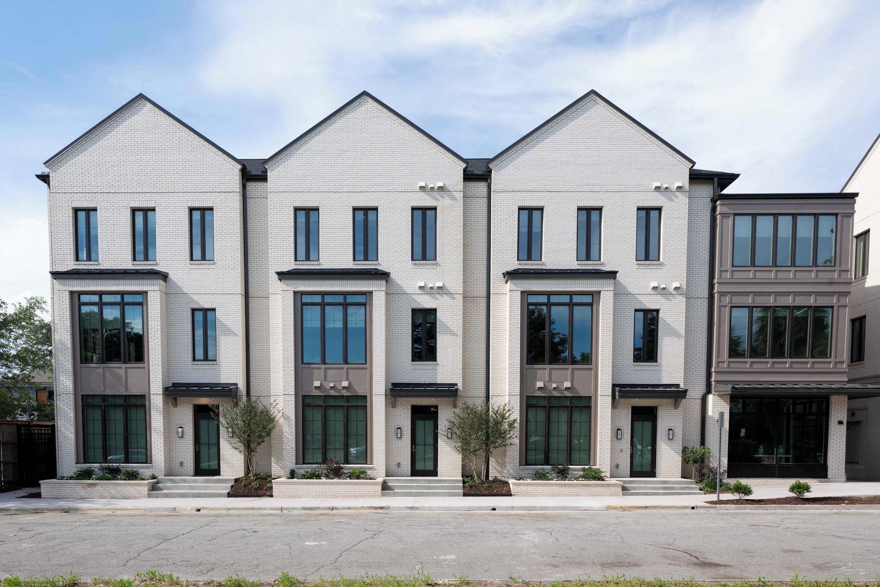 Un moderno edificio residencial de varios pisos con fachada simétrica, ventanas amplias y una entrada central.