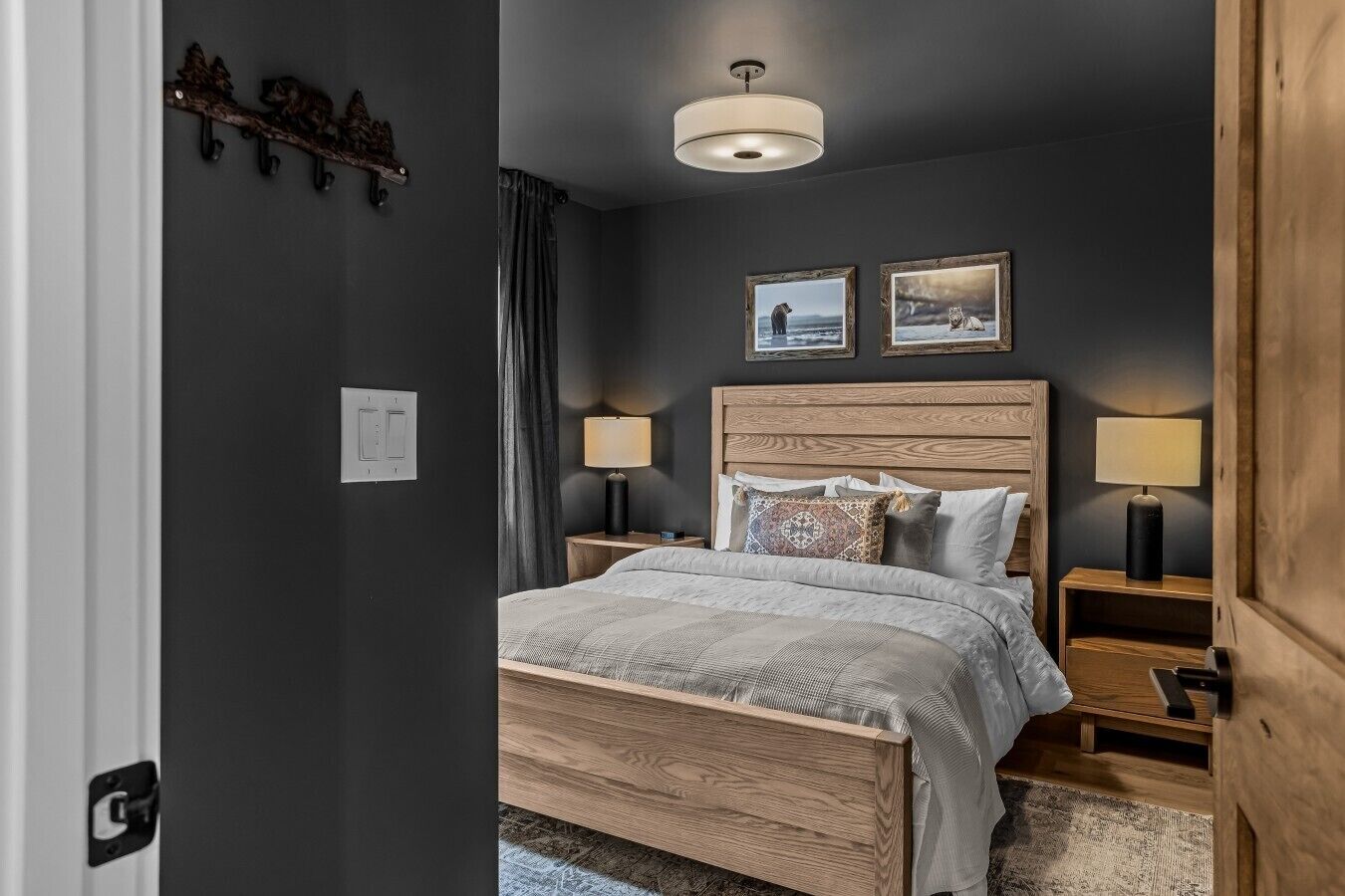 Un dormitorio con una cama de madera, dos lámparas de noche, una lámpara de techo y dos cuadros en la pared.