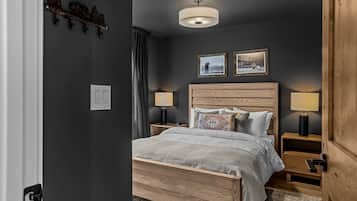 A bedroom with a wooden bed, two bedside lamps, a ceiling light, and two framed pictures on the wall.