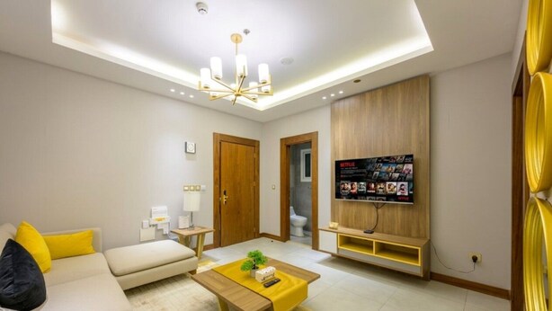 Una sala de estar moderna con sofá, mesa de centro, televisor y mueble de entretenimiento de madera.