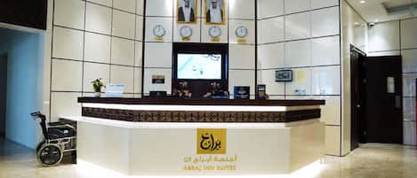 A hotel reception desk with clocks displaying different time zones, a reception area, and a wheelchair.