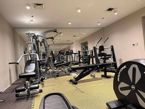 Un gimnasio con diversos equipos de ejercicio, incluyendo cintas de correr, máquinas de pesas y pesas libres.