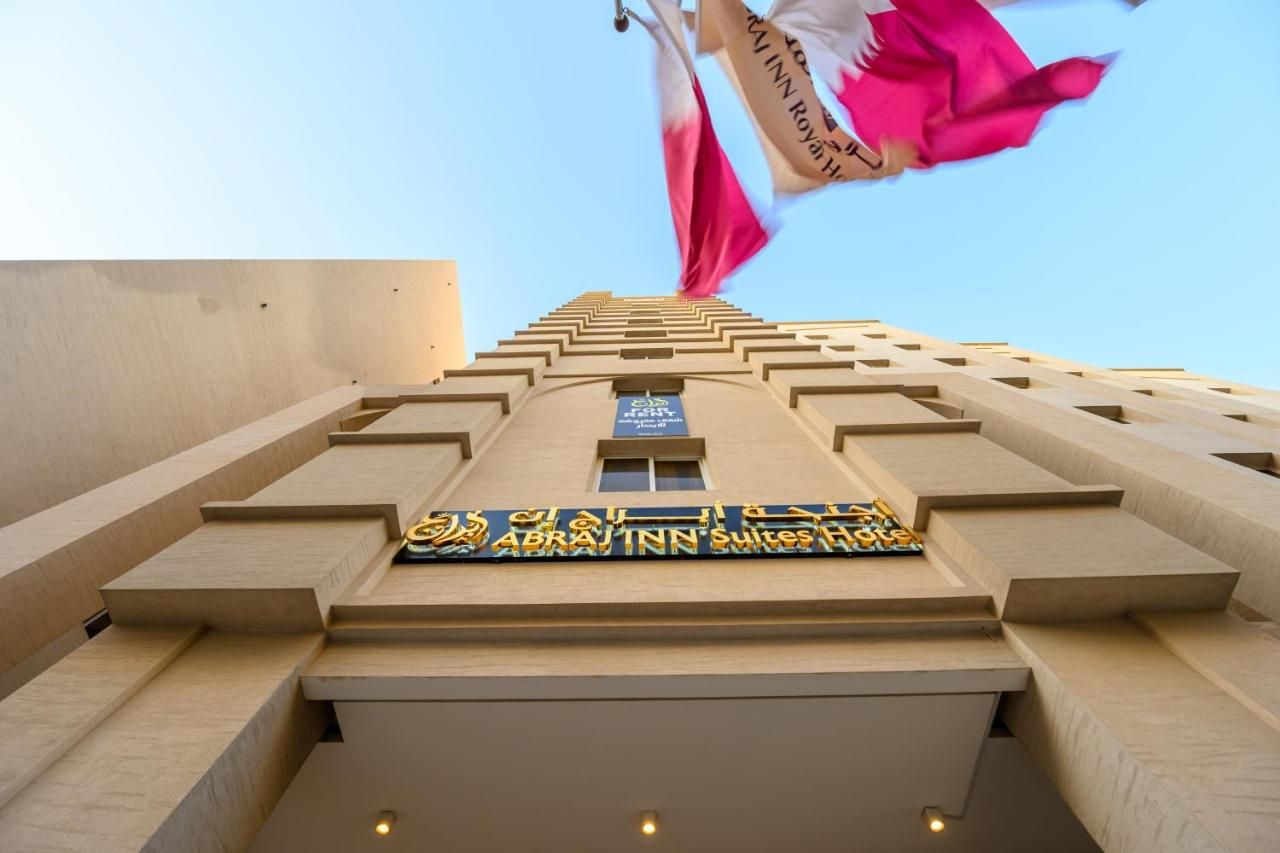 Entrada de un hotel con un letrero que dice 'ABRAH INN Suites Hotel' y una bandera.