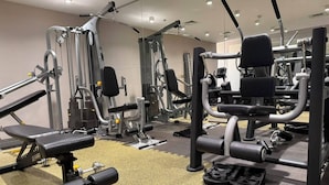 Un gimnasio con diversas máquinas de ejercicio, bancos y pesas.