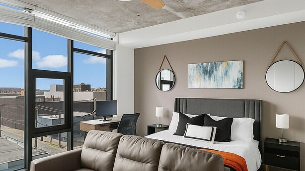 Une chambre d’hôtel moderne équipée d’un grand lit, d’un canapé, d’un bureau et d’un ventilateur de plafond.