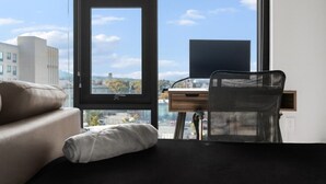 Une pièce moderne dotée d’une grande fenêtre, d’un bureau, d’une chaise et d’un canapé.