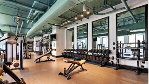 Une salle de sport équipée de matériel d’exercice, dotée de grandes fenêtres et d’un plancher en bois.