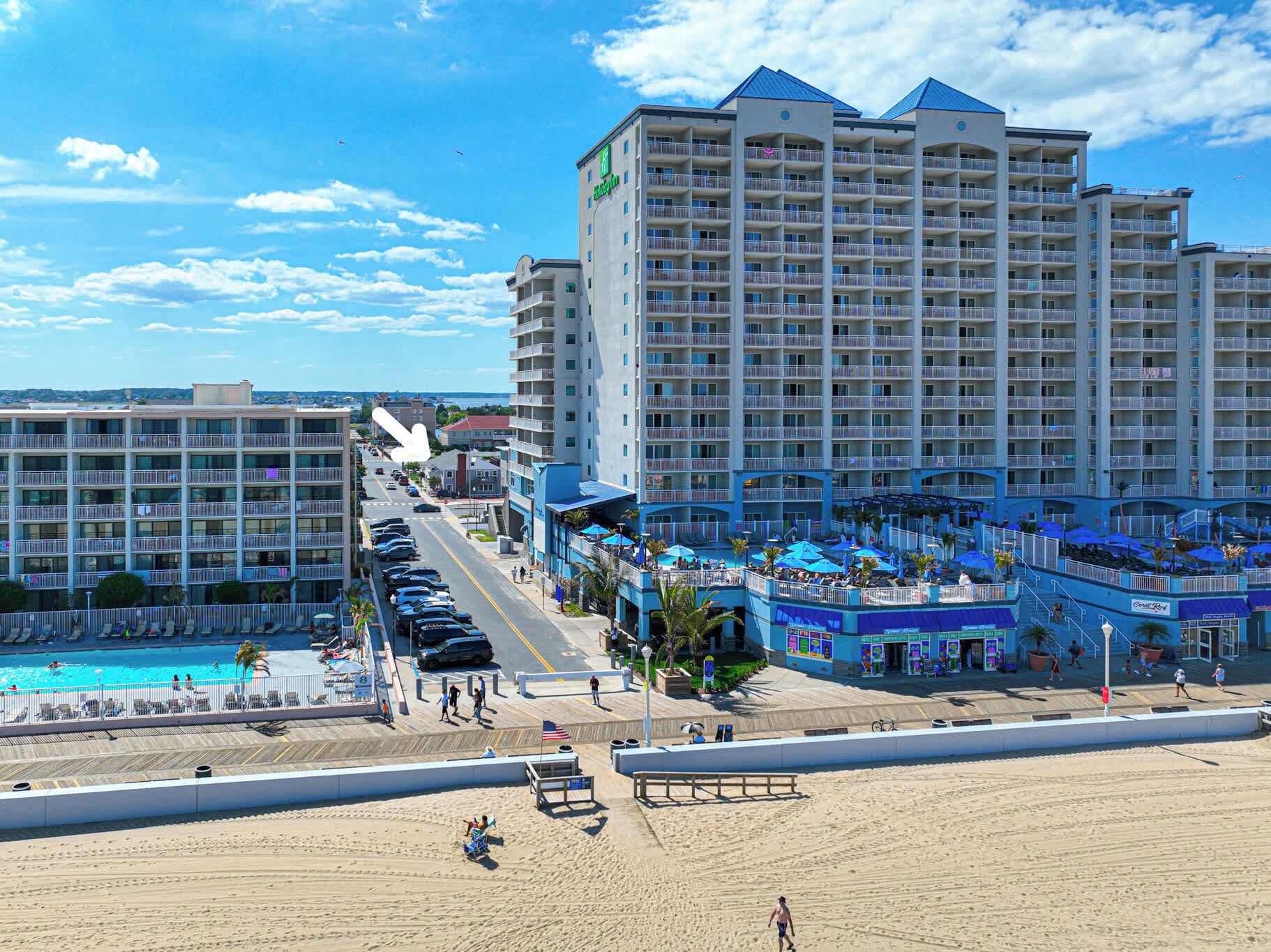 A hotel with multiple floors, a pool area, and a beach.