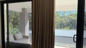 A room with a sliding glass door leading to an outdoor area, a sofa, and a small table. - Luxury Fully Furnished Acreage Retreat – Dural (Dural)