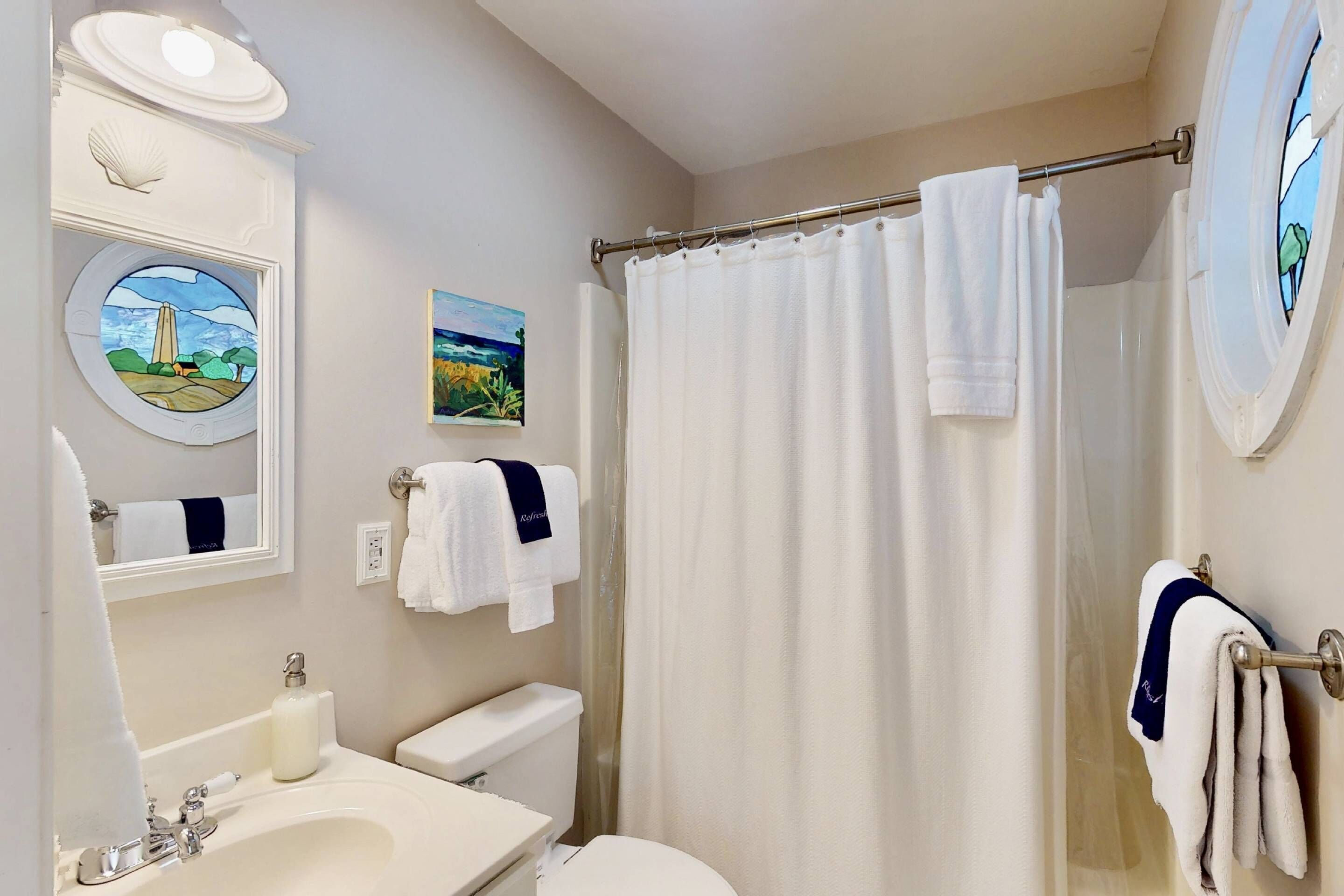 A bathroom with a sink, toilet, shower curtain, and towel racks.