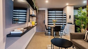 Un espacio de estar moderno con comedor, sofá y televisor montado en la pared.