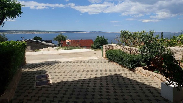 Un vialetto lastricato che conduce a un edificio con vista su un corpo d'acqua e sulla costa in lontananza.