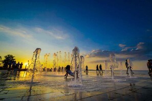 A water feature with multiple fountains, a paved area, and people in the background. - Holiday home near the town centre (Siófok)