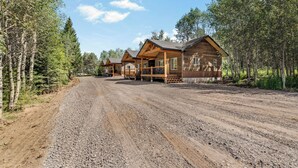 Une cabane en rondins avec un porche et une allée gravillonnée.