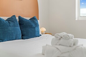 A neatly made bed with blue pillows and a white towel. - 2BR Luxury King Suites + Parking Clean and New (Hallandale Beach)