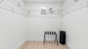 Une petite pièce aux murs blancs, dotée d’un plancher en bois, d’un étendoir métallique et d’un sac noir.