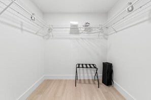 A small, white-walled room with a wooden floor, a metal drying rack, and a black bag. - 2BR Luxury King Suites + Parking Clean and New (Hallandale Beach)