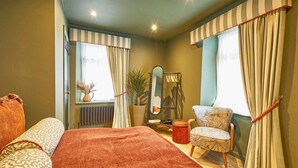 A bedroom with a large bed, a chair, a mirror, and a window with curtains. - Host Stay - Hecklers Nook (Barnard Castle)