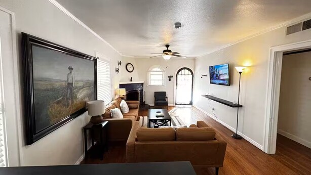 Un salon avec une cheminée, un téléviseur fixé au mur et un ventilateur de plafond.