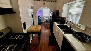 Une cuisine étroite comprenant un fourneau, un évier et un petit coin repas avec une table et des chaises.