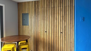 A room with a wooden slat wall, a round table, and yellow chairs.