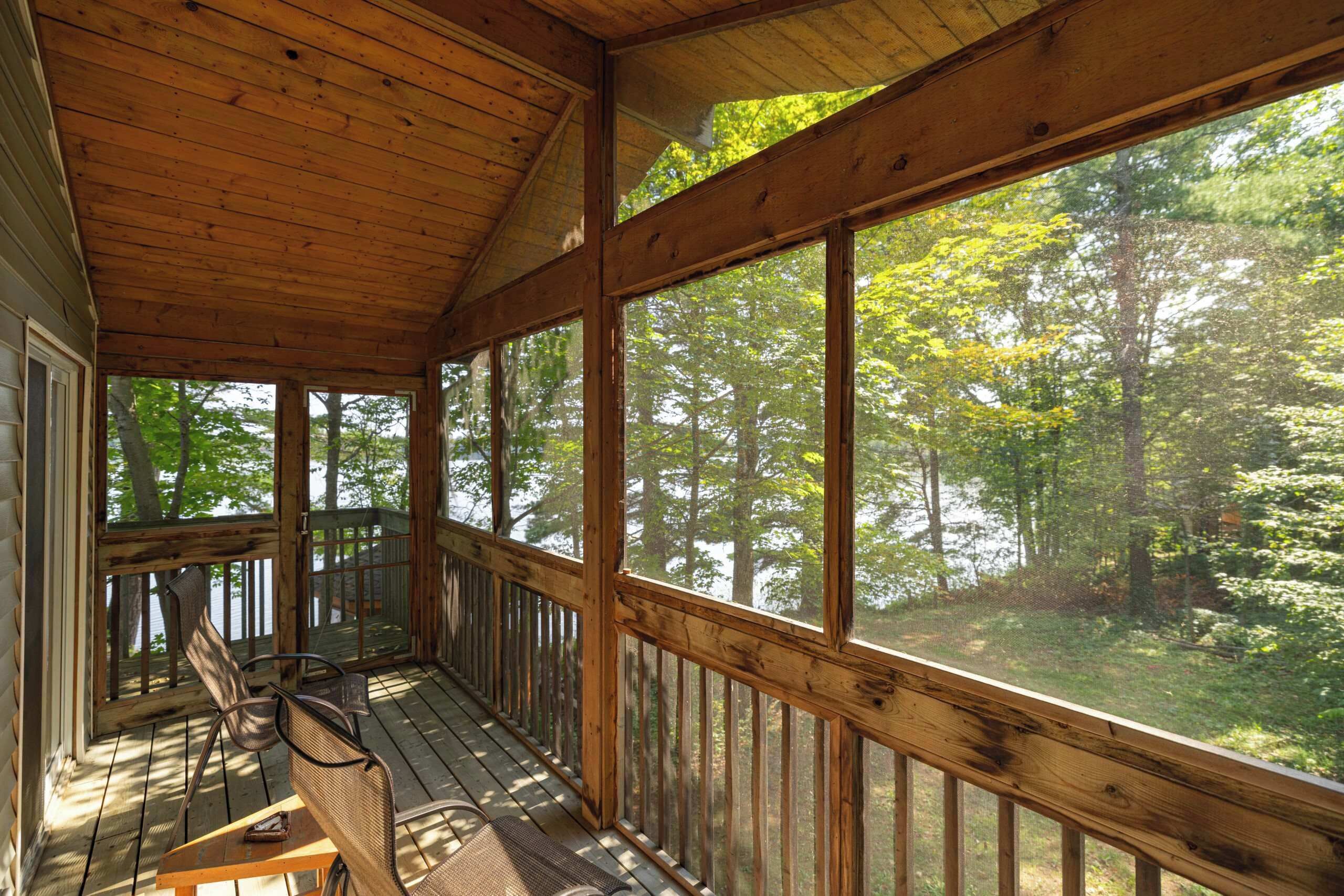 A wooden deck with a view of a forest and a lake.